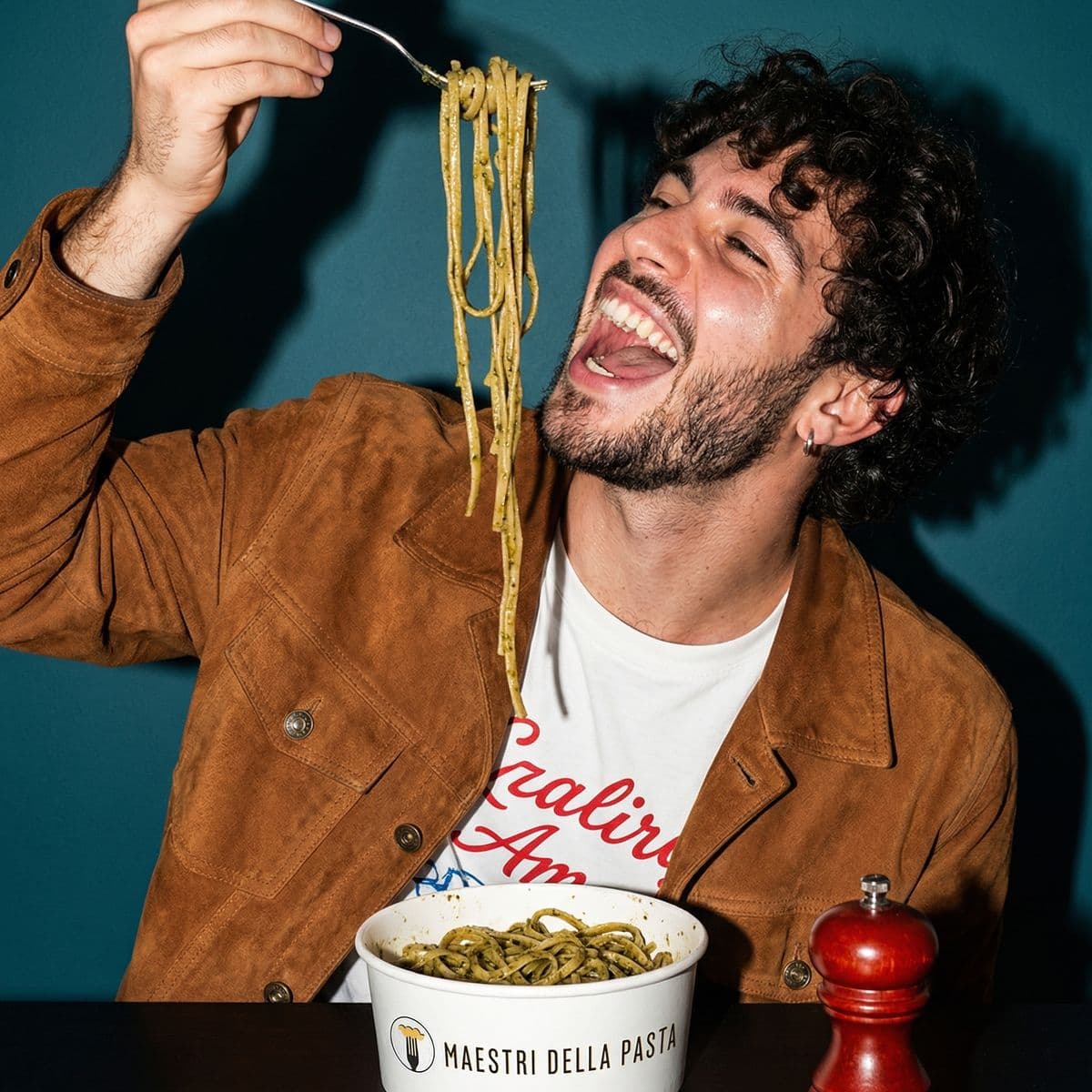 Man laughing while eating pesto spaghetti at Maestri della Pasta