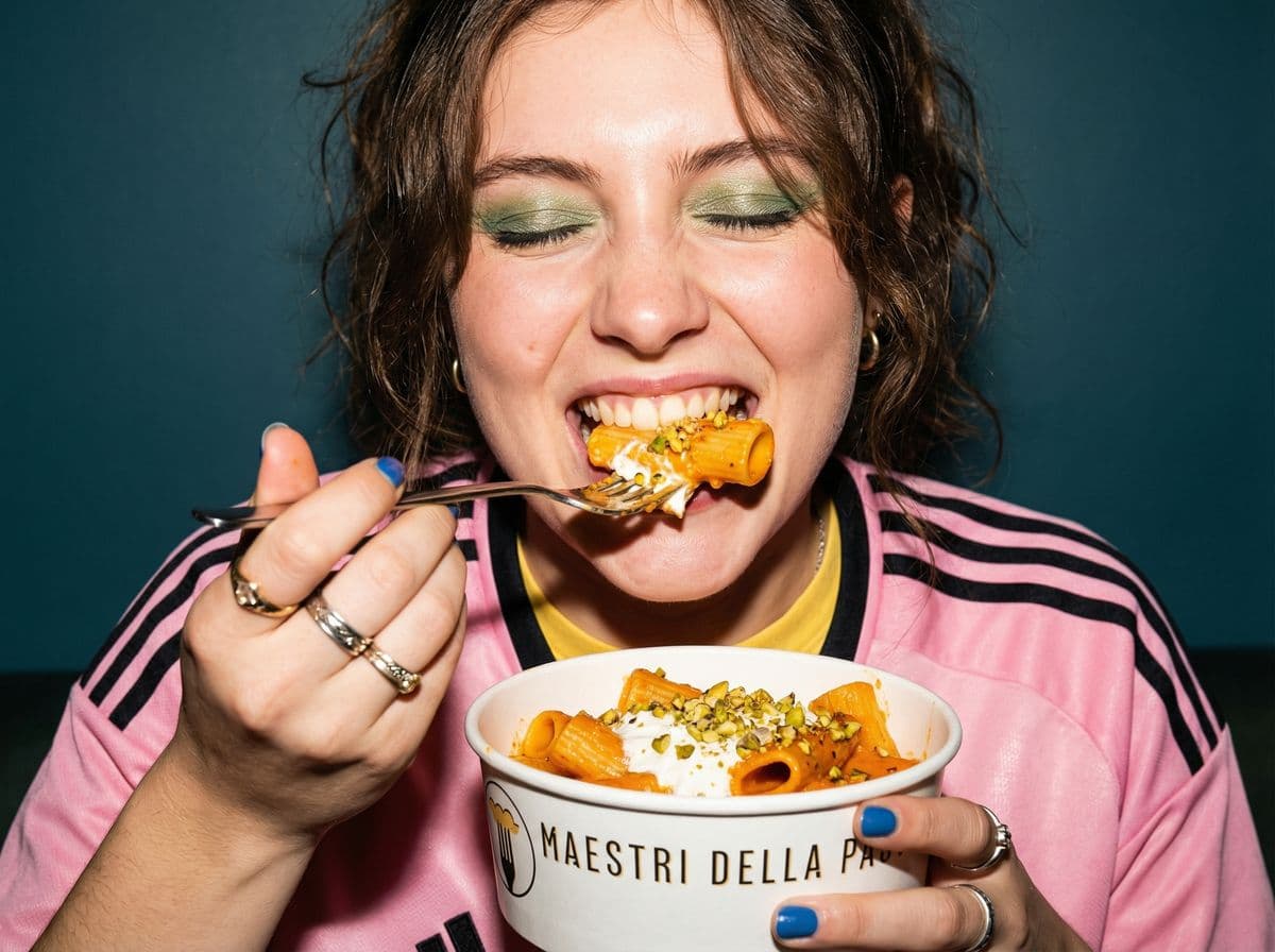 Close-up of woman biting into rigatoni at Maestri della Pasta